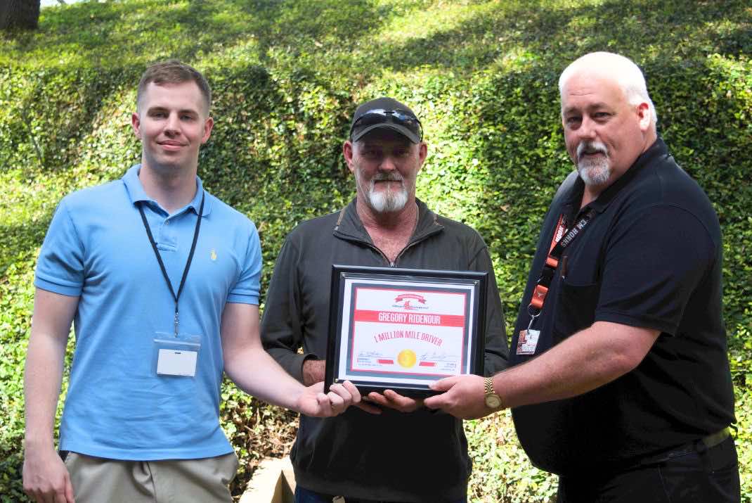 Image of three men, Gregory Ridenour in the middle holding million miler award